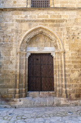 The old wooden door in the ornate stone wall of the church
