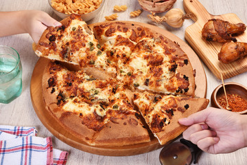 People hands taking slices of salmon with cream sause pizza   