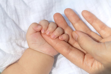 Obraz na płótnie Canvas Baby uses his small fingers to hold his mother's finger to make him feel love, warm and secure while he is sleeping