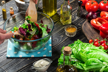 Man preparing salad with fresh vegetables on a wooden table. Cooking tasty and healthy food. Close-up