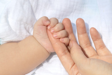 Obraz na płótnie Canvas Baby uses his small fingers to hold his mother's finger to make him feel love, warm and secure while he is sleeping