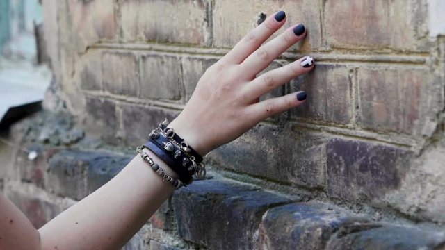 Women's hand with a black wristband moving along the brick wall. Slow motion. HD