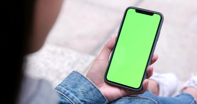 Woman holding cellphone with green screen