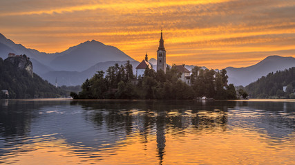 Fototapeta na wymiar Lake bled with church under orange morning sky