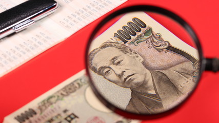 一万円札と拡大鏡と通帳と印鑑