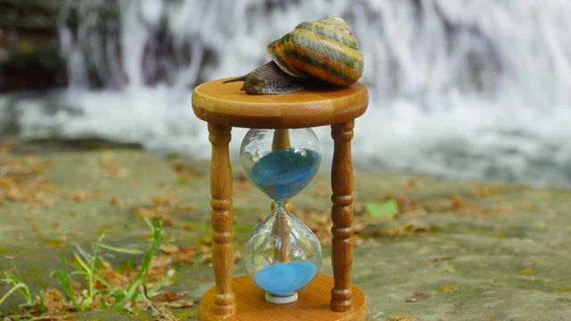 Hourglass on the Background of a Mountain River