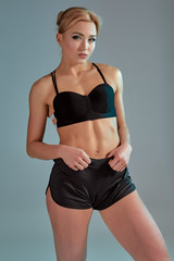 Fototapeta na wymiar Fitness woman in black tank top and shorts, studio shot.