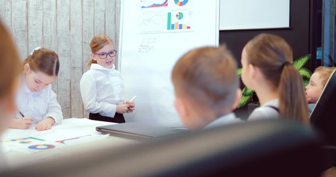 Female manager presents a new project plan to colleagues at a meeting, explaining ideas about a flip chart for colleagues in the office, a businessman giving a presentation. Business children