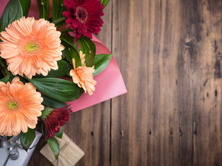 Bouquet of flowers on blurred wooden background, top view. Gift boxes on backdrop. Decoration made of chrysanthemums, daisies decorative plants for birthday card. Selective soft focus