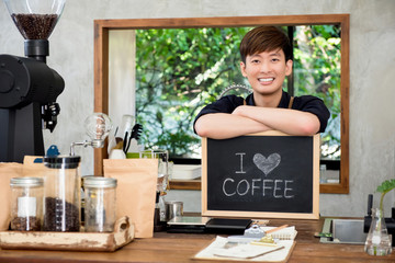 Fototapeta na wymiar Cheerful young Asian man entrepreneur at counter in coffee shop