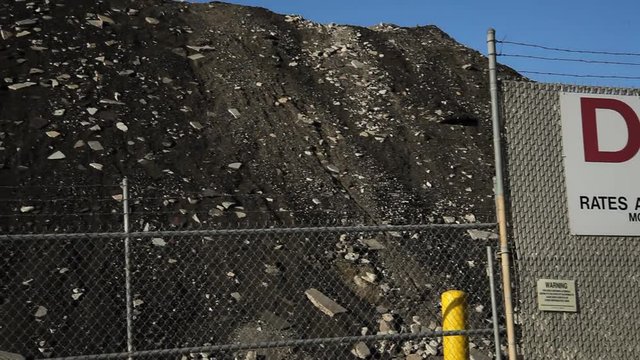 A mound of waste material inside chain-link fencing at a closed dump site