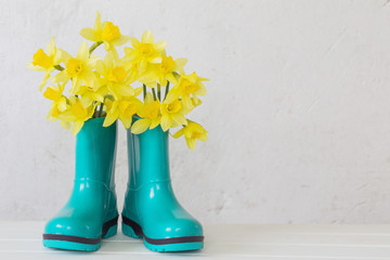 rubber boots and spring flowers on white background