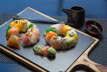 Vegan sushi donuts set with ginger, avocado, cucumber, chives served on stone slate. Sushi-food hybrids trend. high-end cuisine