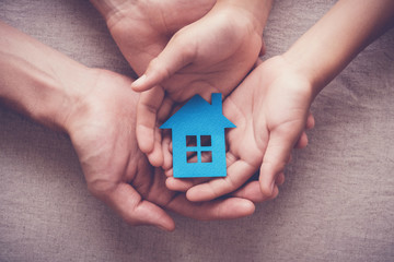 Adult and child hands holding paper house, family home, homeless shelter, foster home care, family...