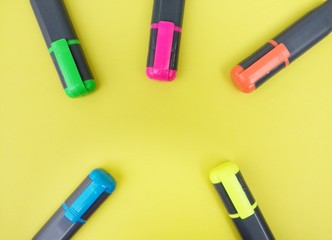 Highlighter pens and the caps on yellow background, with copy space