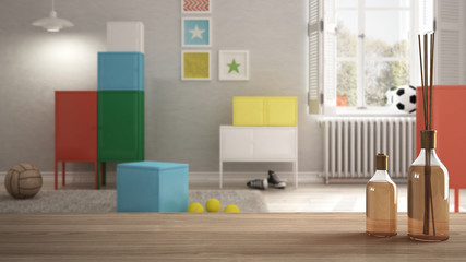 Wooden table top or shelf with aromatic sticks bottles over blurred colorful children bedroom, white architecture interior design