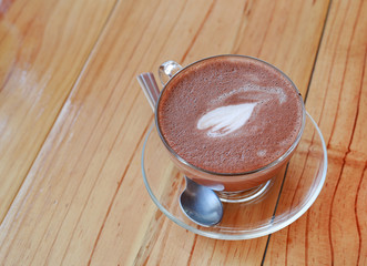 Cup of hot cocoa with heart shape on the wooden table.