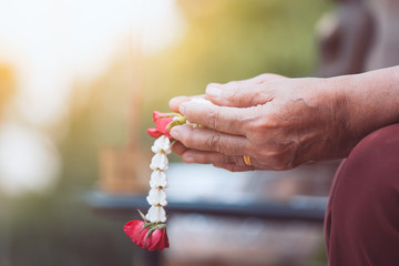 Hand of elder senior holding beautiful flower garlands for celebrate Songkran in new year water festival. 