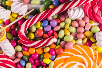 Fototapeta na wymiar Background of colorful chocolate candies, lollipops, candy cane and marshmallows