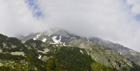 Panorama of a beautiful mountain summit in a fog at sunny day