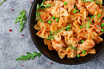 Farfalle pasta with chicken fillet, tomato sauce and green peas. Italian Cuisine. Food menu. Top view. Dinner.