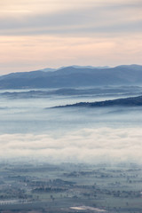 Beautiful aerial view of Umbria valley in a winter morning, with fog covering trees and houses