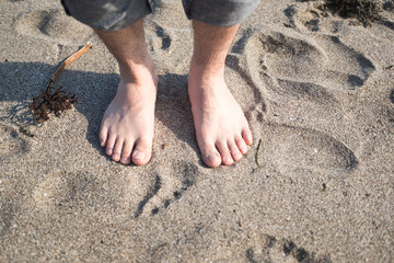 砂浜に立つ男性の足
