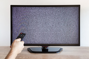 Man's hand holding tv remote. Searching, installing or checking tv channels. White noise. No...