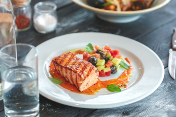 plate of grilled salmon steak with vegetables on wooden table