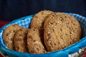 homemade oat cookies with sunflower seeds in and near blue checkered basket on wooden table