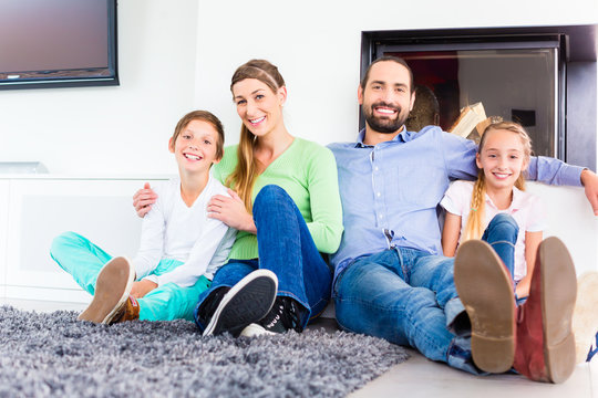 Happy family sitting at living room floor fireplace