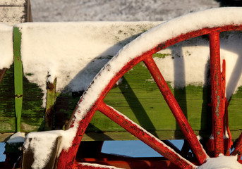 Red wooden Wagon wheel and snow
