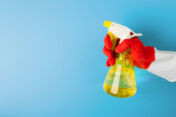A hand in a red glove holds a spray of cleaning fluid