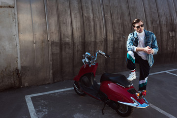 Fototapeta na wymiar serious man in stylish denim jacket with vintage scooter on parking