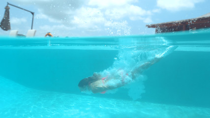 Fototapeta na wymiar HALF-HALF: Caucasian woman on tranquil vacation dives into cool emerald water.