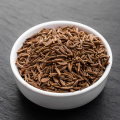 Seeds of cumin on a dark stone background