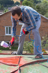 roofer worker with pulverizer spraying paint
