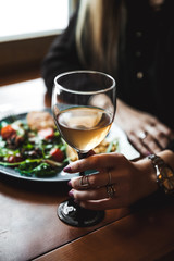 Female hand with glass of wine and food in the background