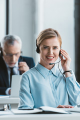 beautiful businesswoman using headset and smiling at camera