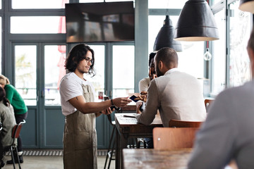 Waiter accepting payment from customer in cafe