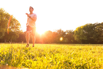 A handsome young man running during sunset in a park
