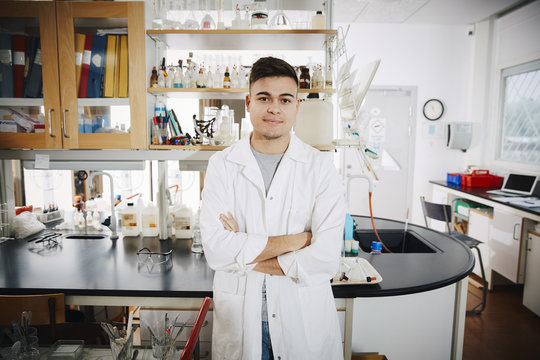 Portrait of young male student standing with arms crossed in chemistry laboratory