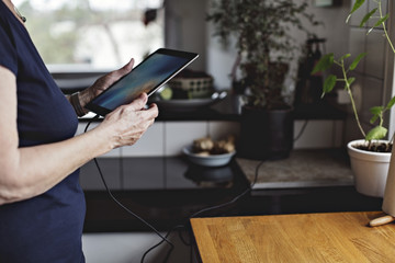 Midsection of senior woman using digital tablet in kitchen at home
