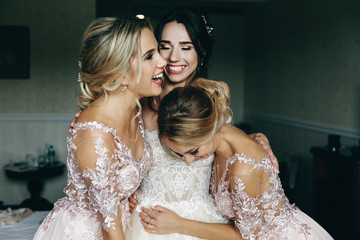 Naklejka premium Bride and bridesmaids laugh posing before an open balcony in a hotel room