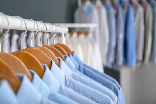 Rack with clean clothes on hangers after dry-cleaning indoors