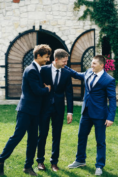 Crazy groom and groomsmen have fun posing on the backyard outside
