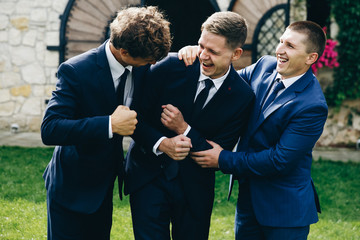 Crazy groom and groomsmen have fun posing on the backyard outside