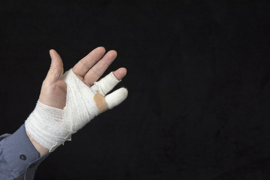 Close up of a injured, bandaged hand on a black background 