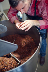 Picture of young businessman with coffee beans in hand next to roaster