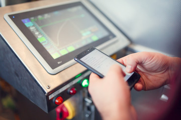 Photo of computer monitor, person's hands with smartphone